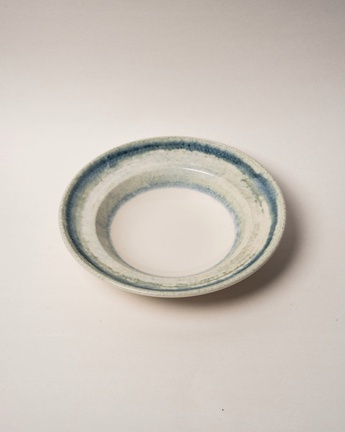 Tilted side view of Atlantis porcelain bistro bowl, blue rim design
