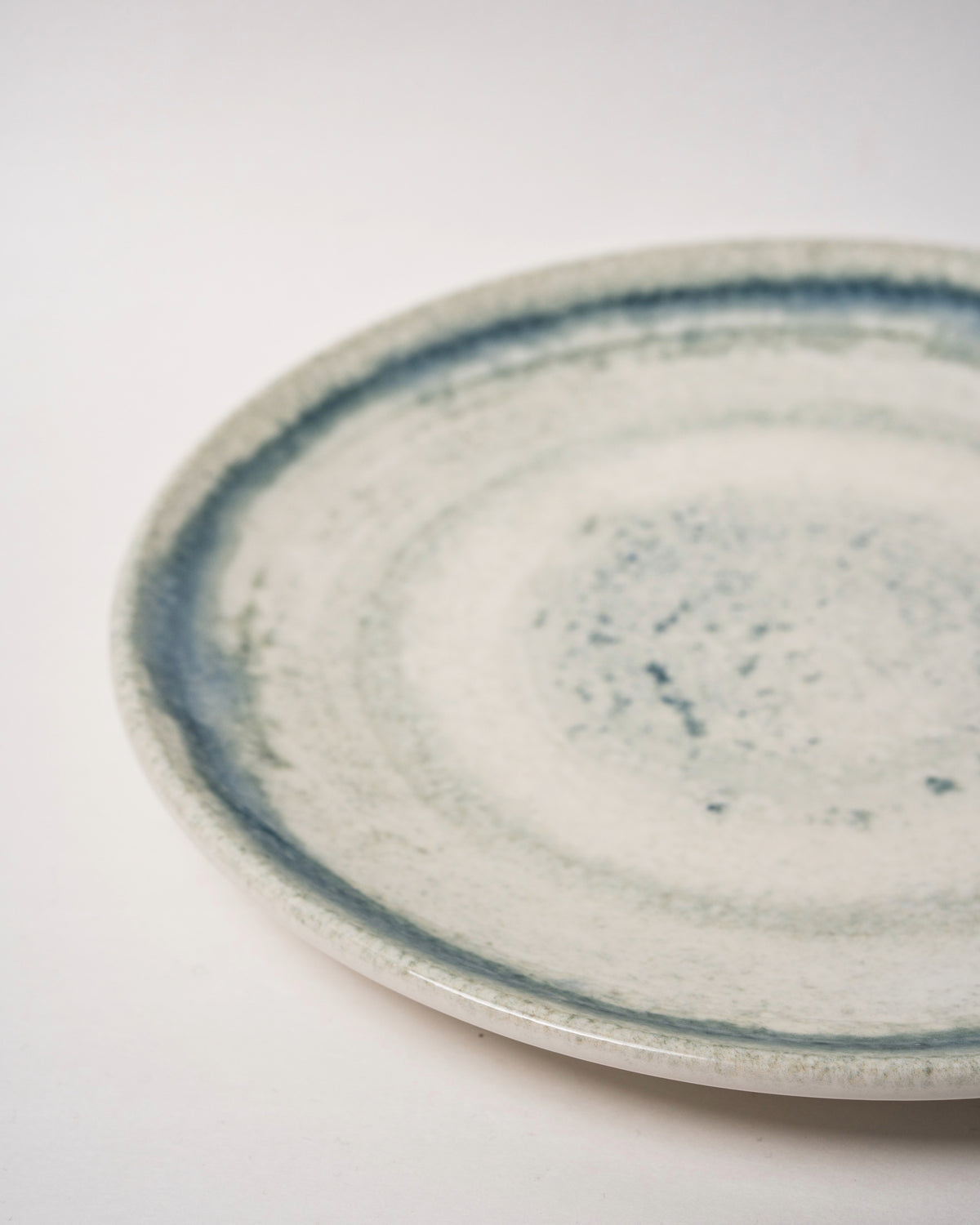 Atlantis porcelain dinner plate viewed at an angle, blue rim and white center