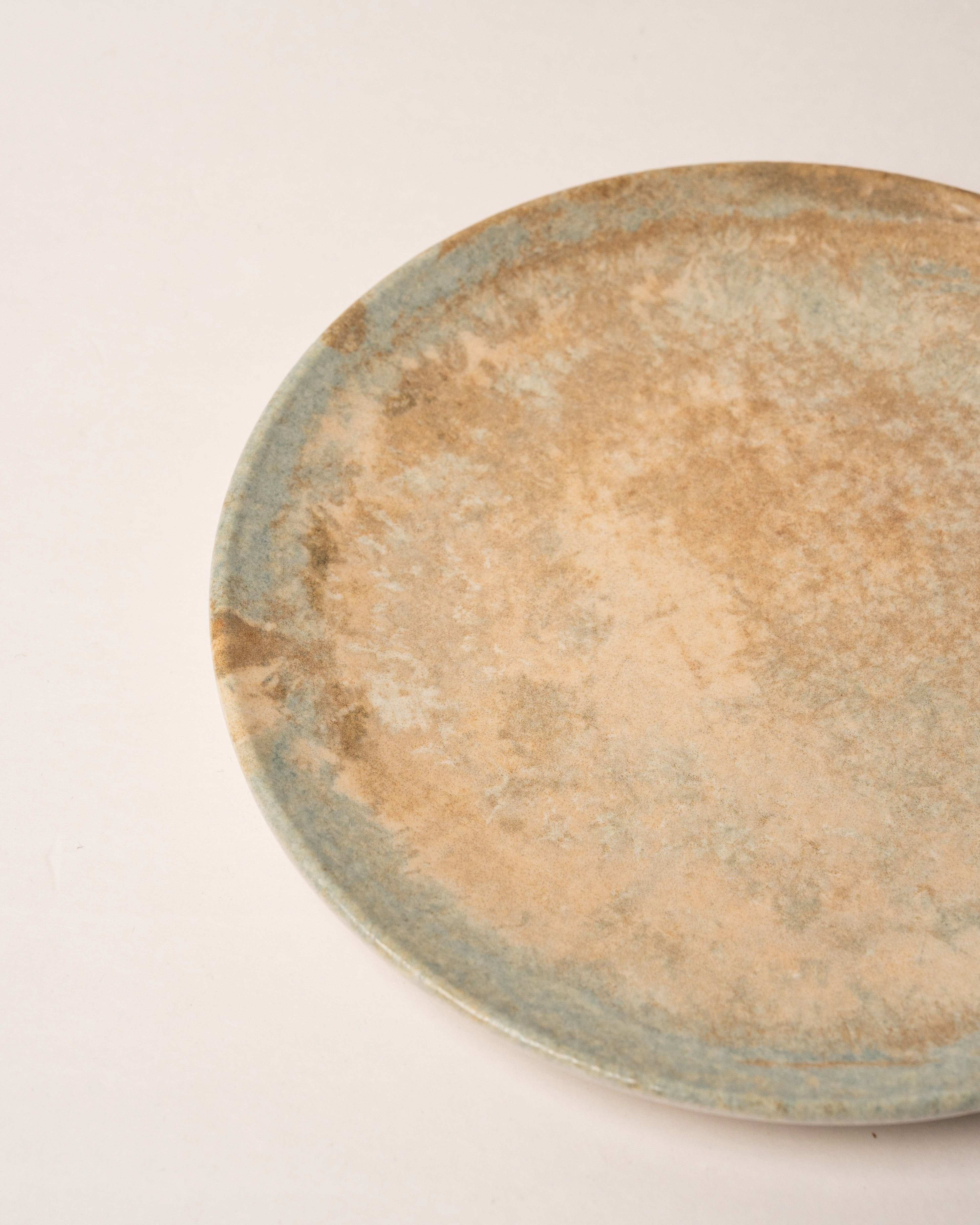 Angled view of Aurelia porcelain dinner plate showing bronze glaze detail