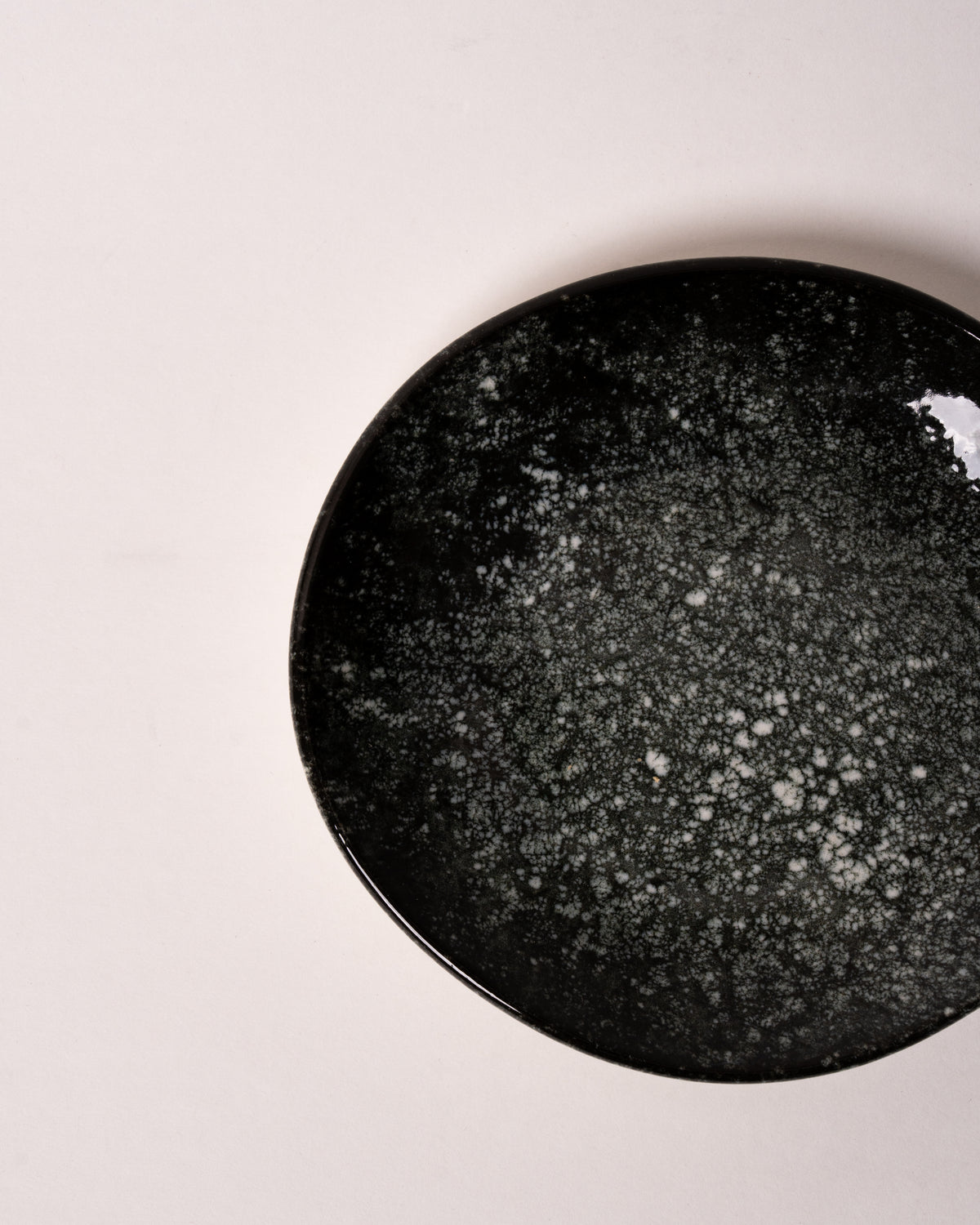 Cosmos porcelain small plate in grey glaze, angled view