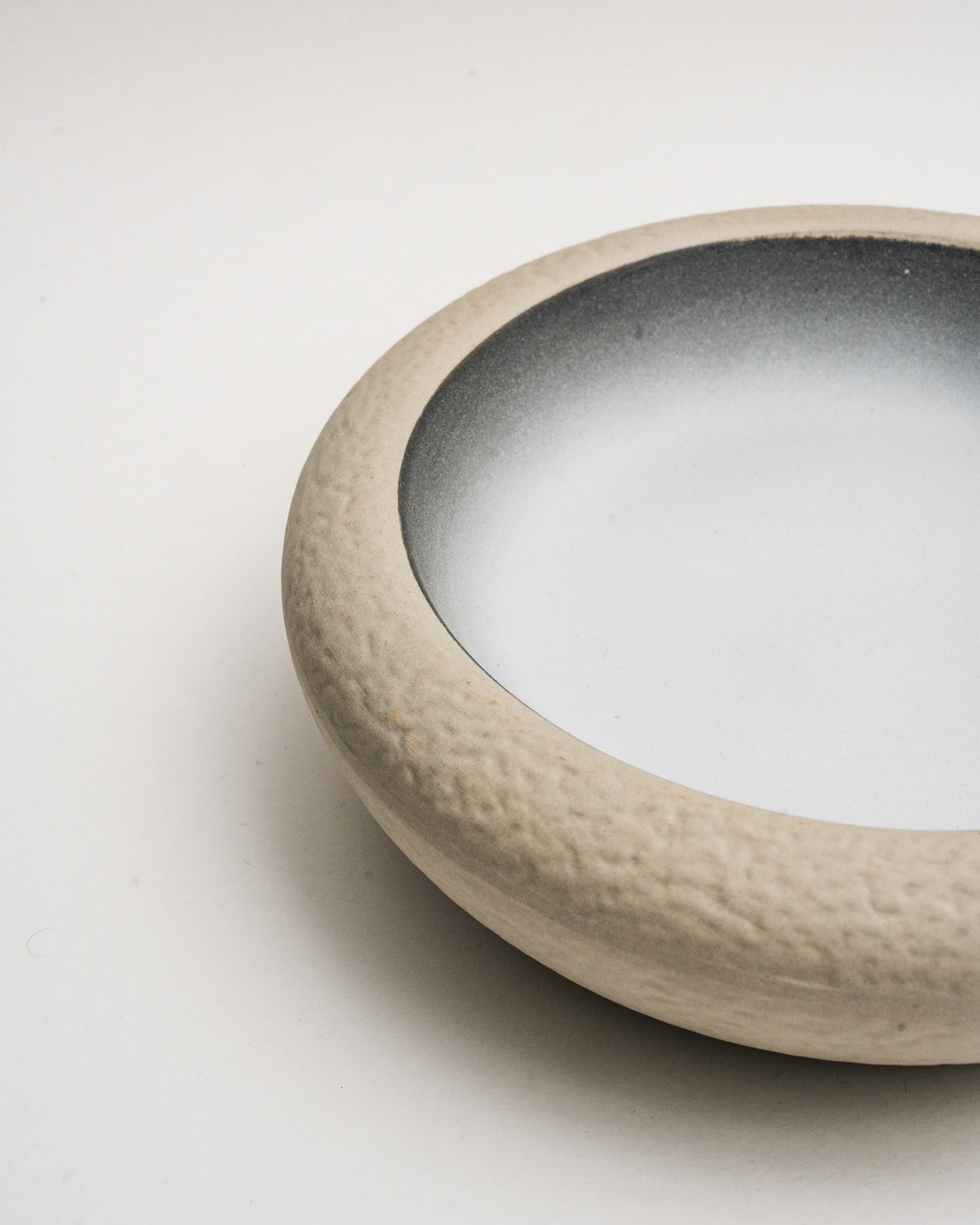 Angled view of Crater porcelain bistro bowl, stone rim detail