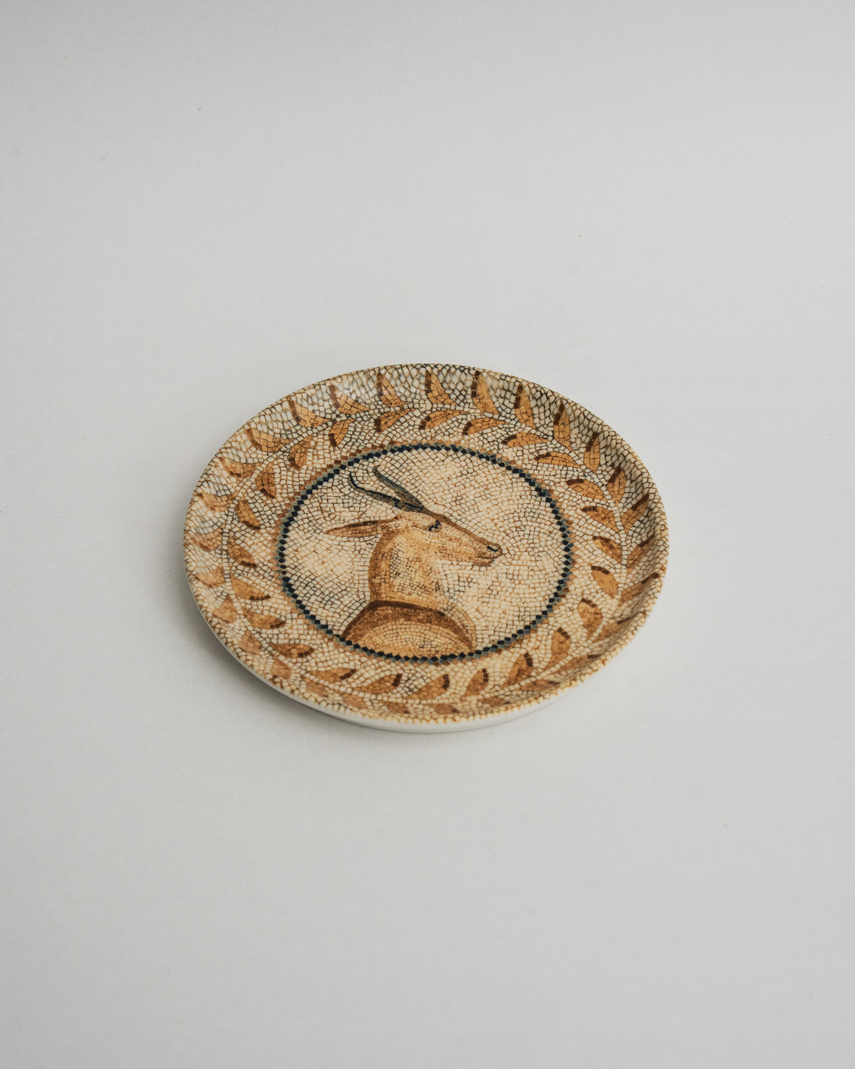 Angled view of Deer Mosaïque porcelain plate, tan and gold mosaic pattern