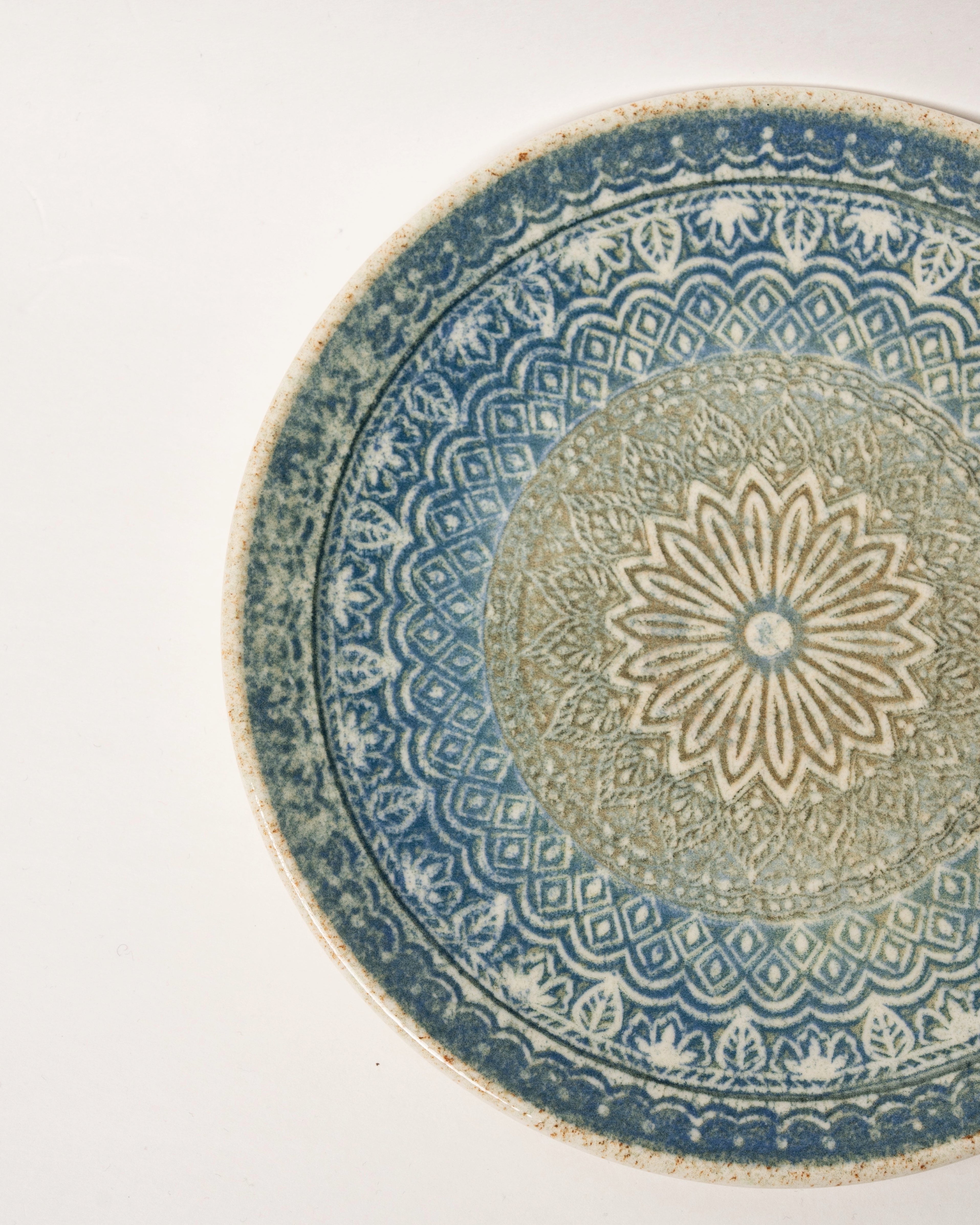 Angled view of Embroideries of Atlantis porcelain plate showing rim and pattern detail