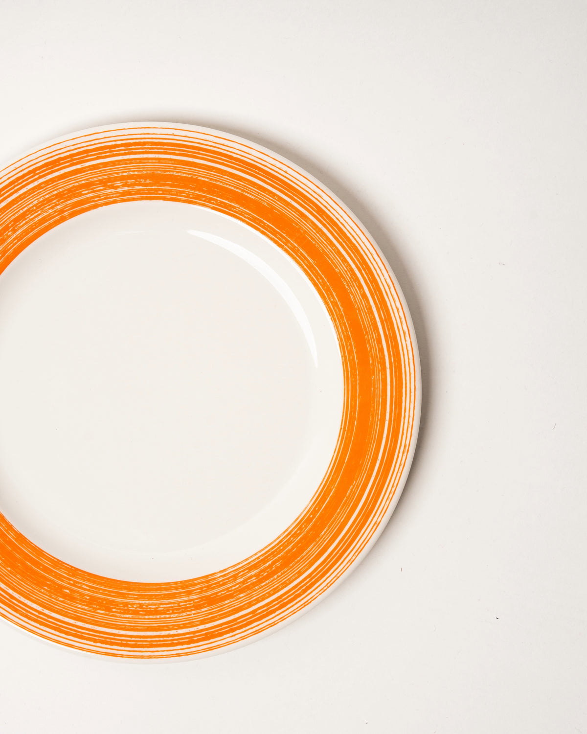 Angled view of Fresh Orange porcelain dinner plate, orange and white finish