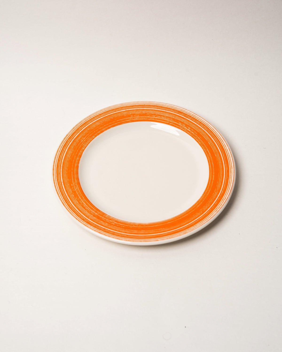 Close view of Fresh Orange porcelain dinner plate rim, orange glaze detail