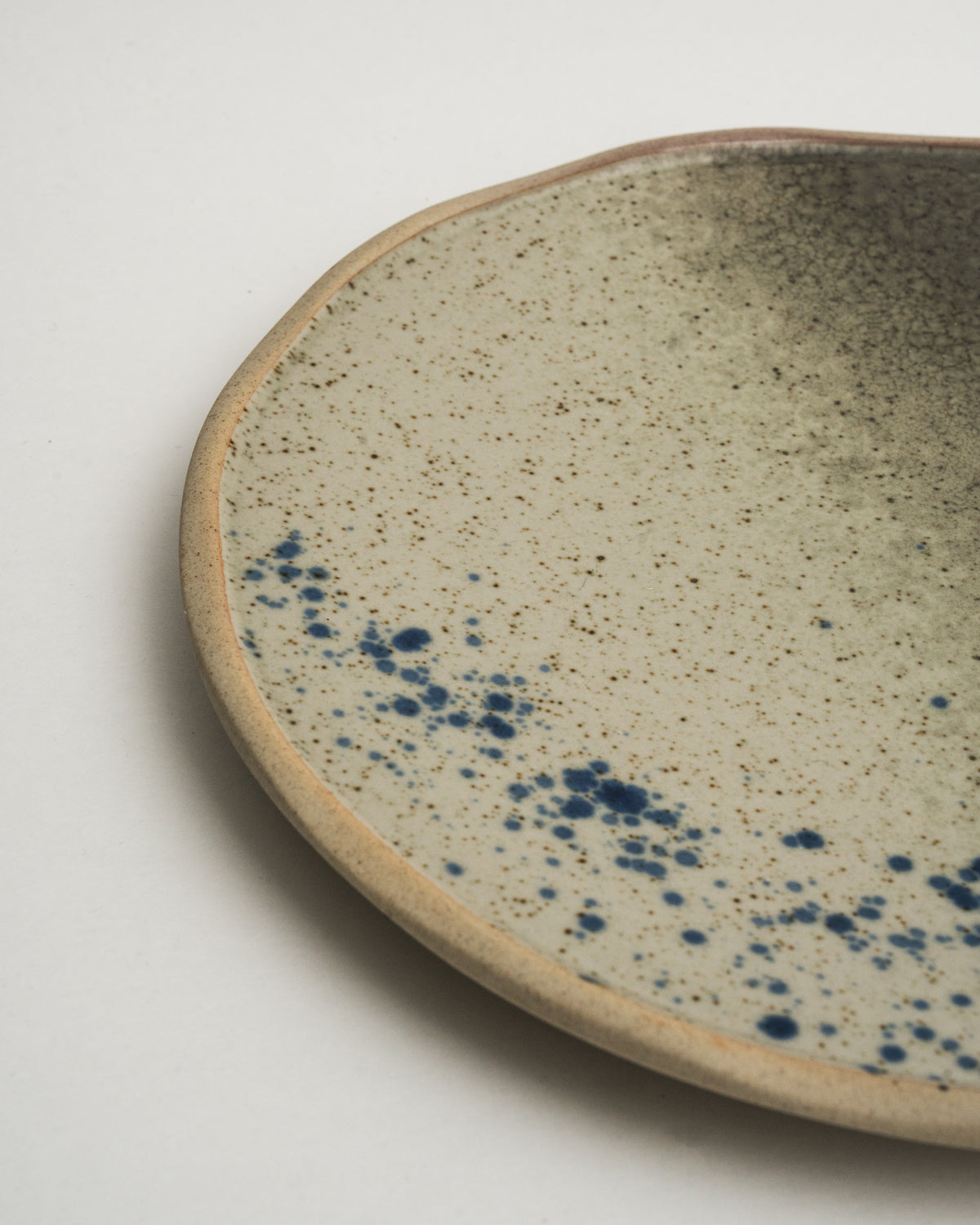 Angled view of Gaia porcelain dinner plate, blue-grey finish