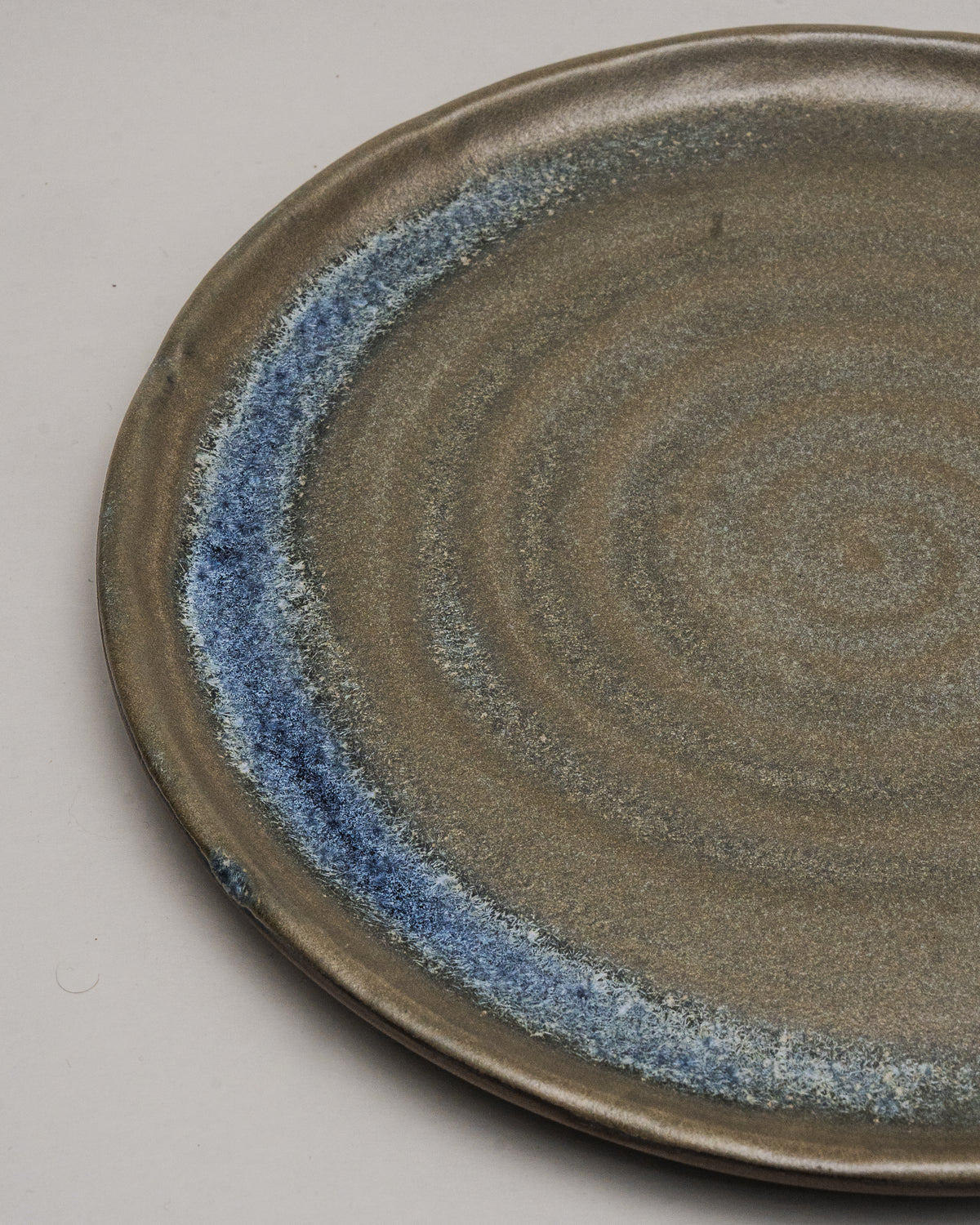 Angled view of Lagoon porcelain dinner plate, stone-toned finish