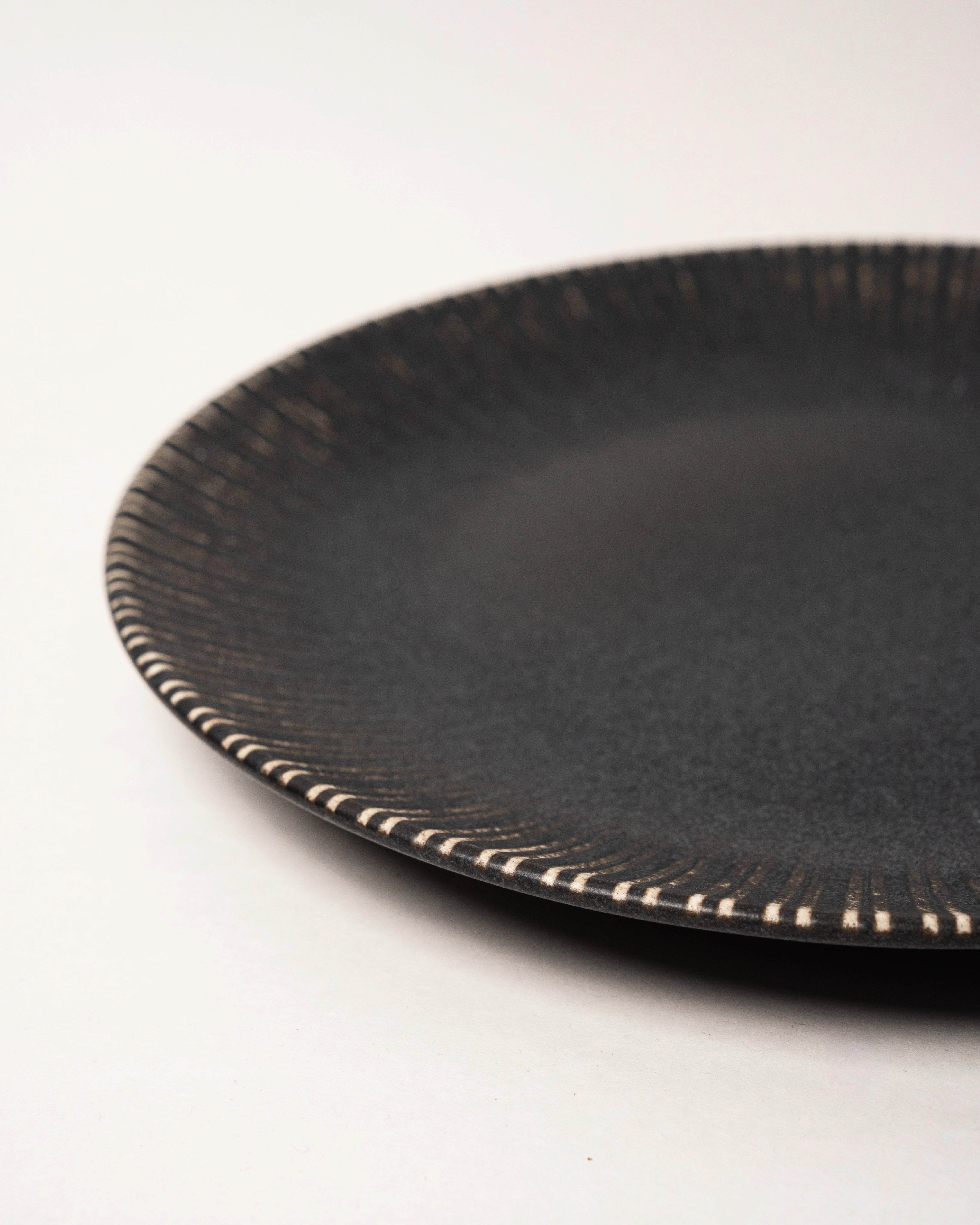 Angled view of Obsidian porcelain dinner plate showing beaded rim detail