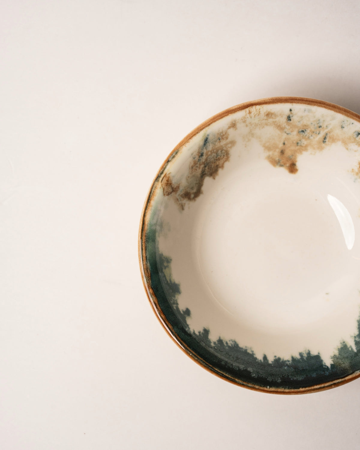 Angled tilted view of Pelagos porcelain bowl, teal and gold rim