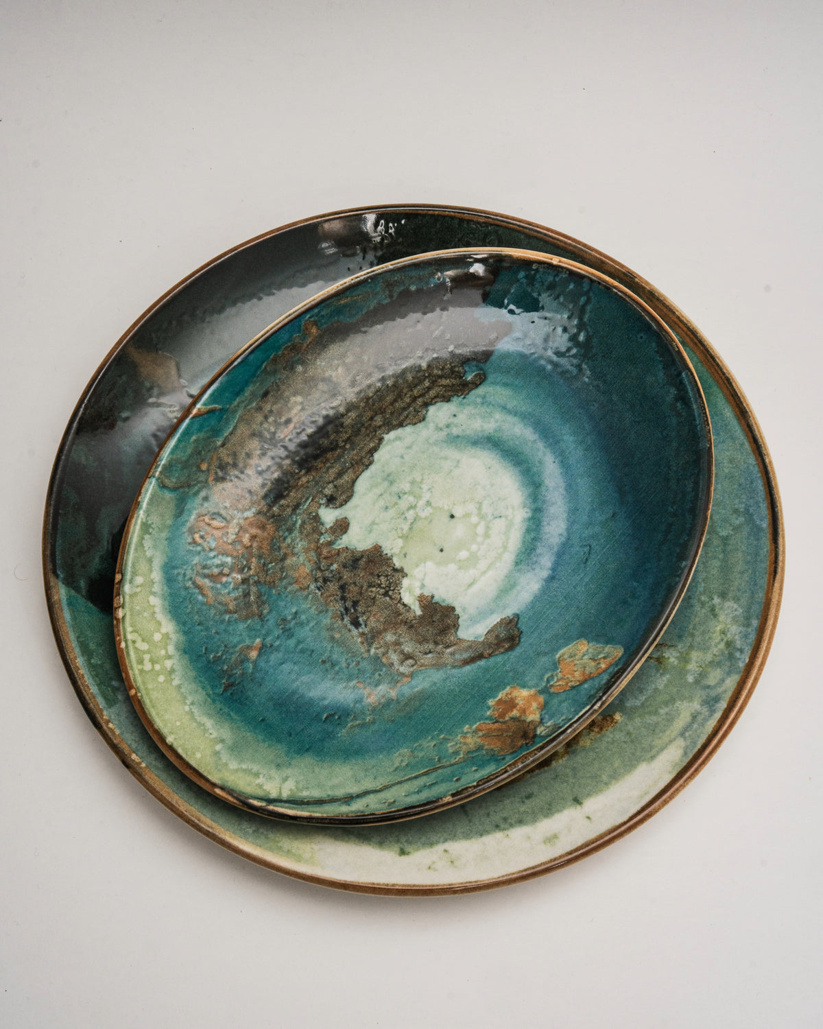Close overhead view of Pelagos porcelain oval plate, teal and gold texture