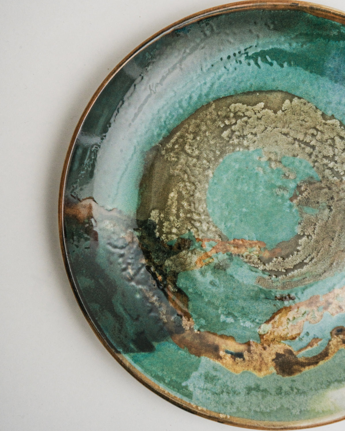 Angled view of Pelagos porcelain dinner plate, teal and gold finish