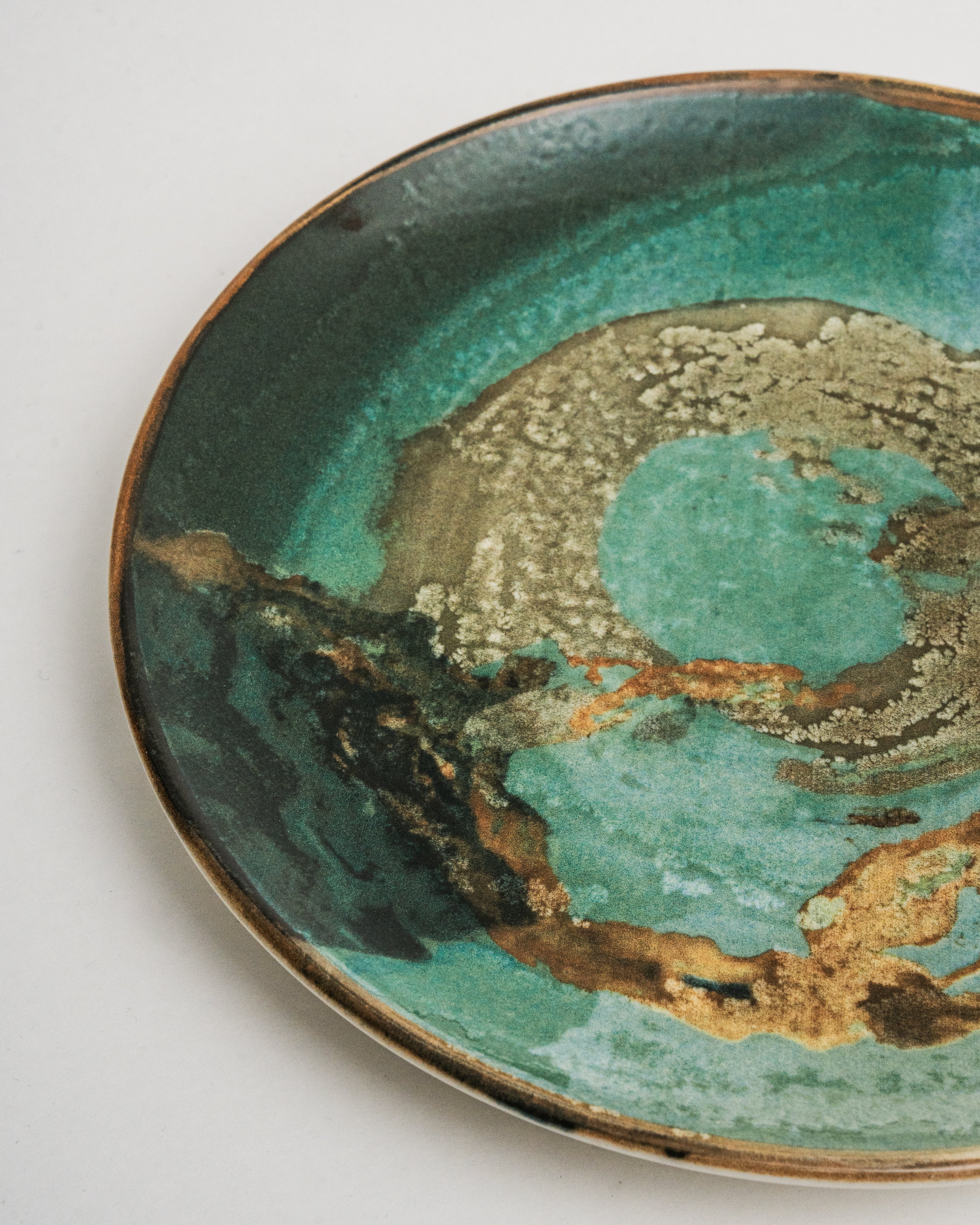 Overhead view of Pelagos porcelain dinner plate showing teal and gold glaze
