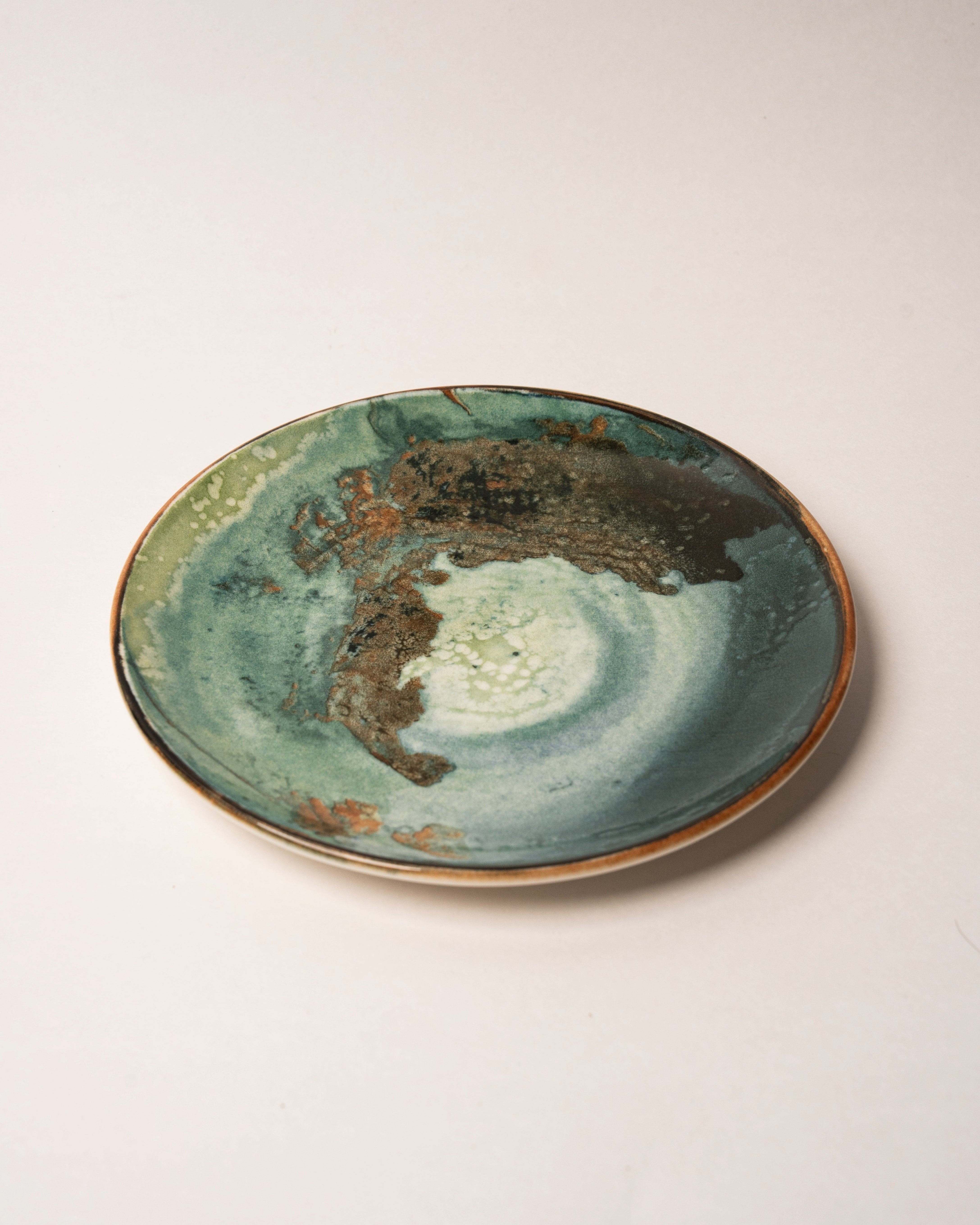 Close-up of Pelagos porcelain plate, teal and gold glaze texture