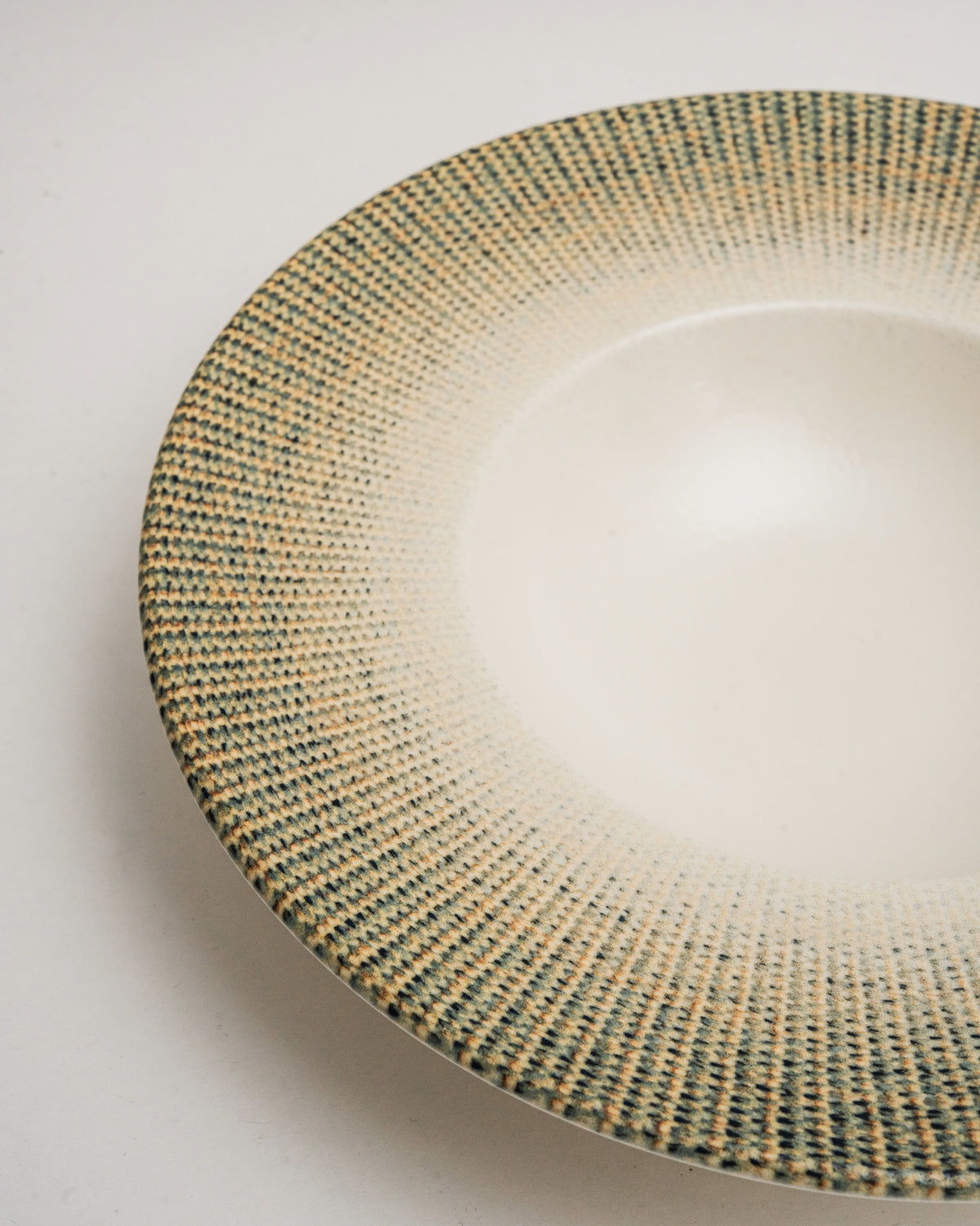 Angled view of Python porcelain banquet plate, olive rim and cream center
