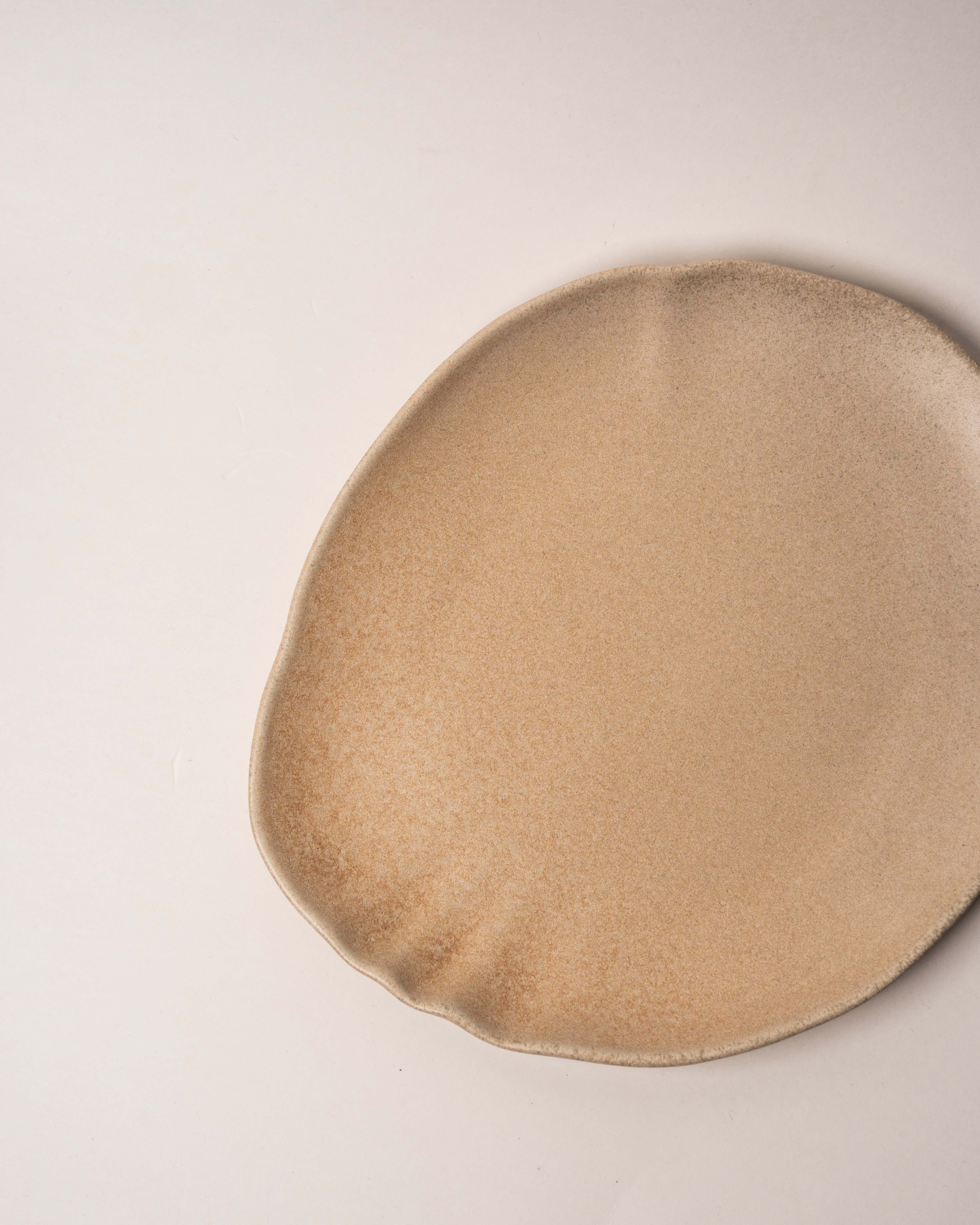 Angled view of Sahara porcelain dinner plate showing sand-toned finish