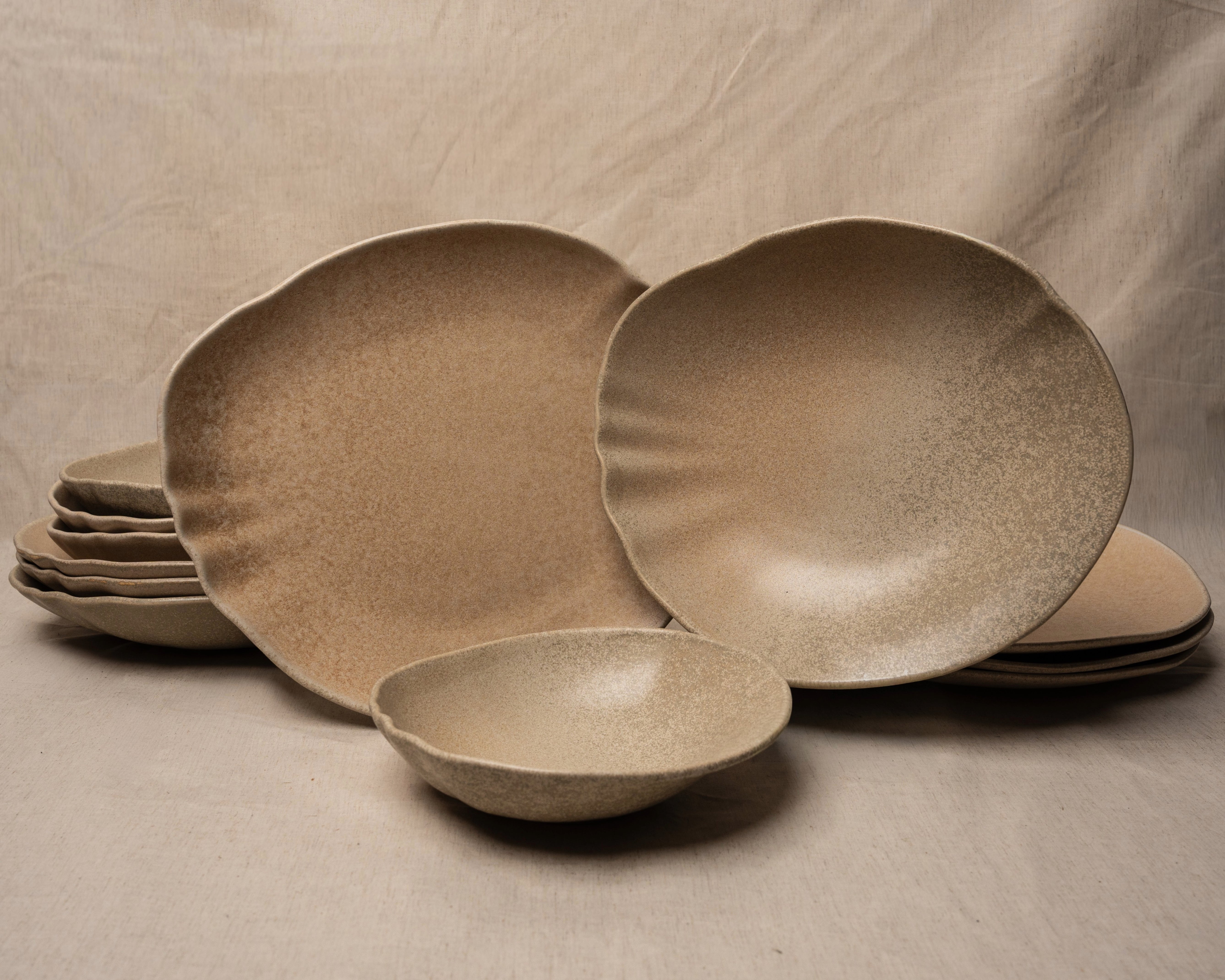 Sahara porcelain dinnerware set, 12 pieces, sand-toned plates and bowls stacked on linen