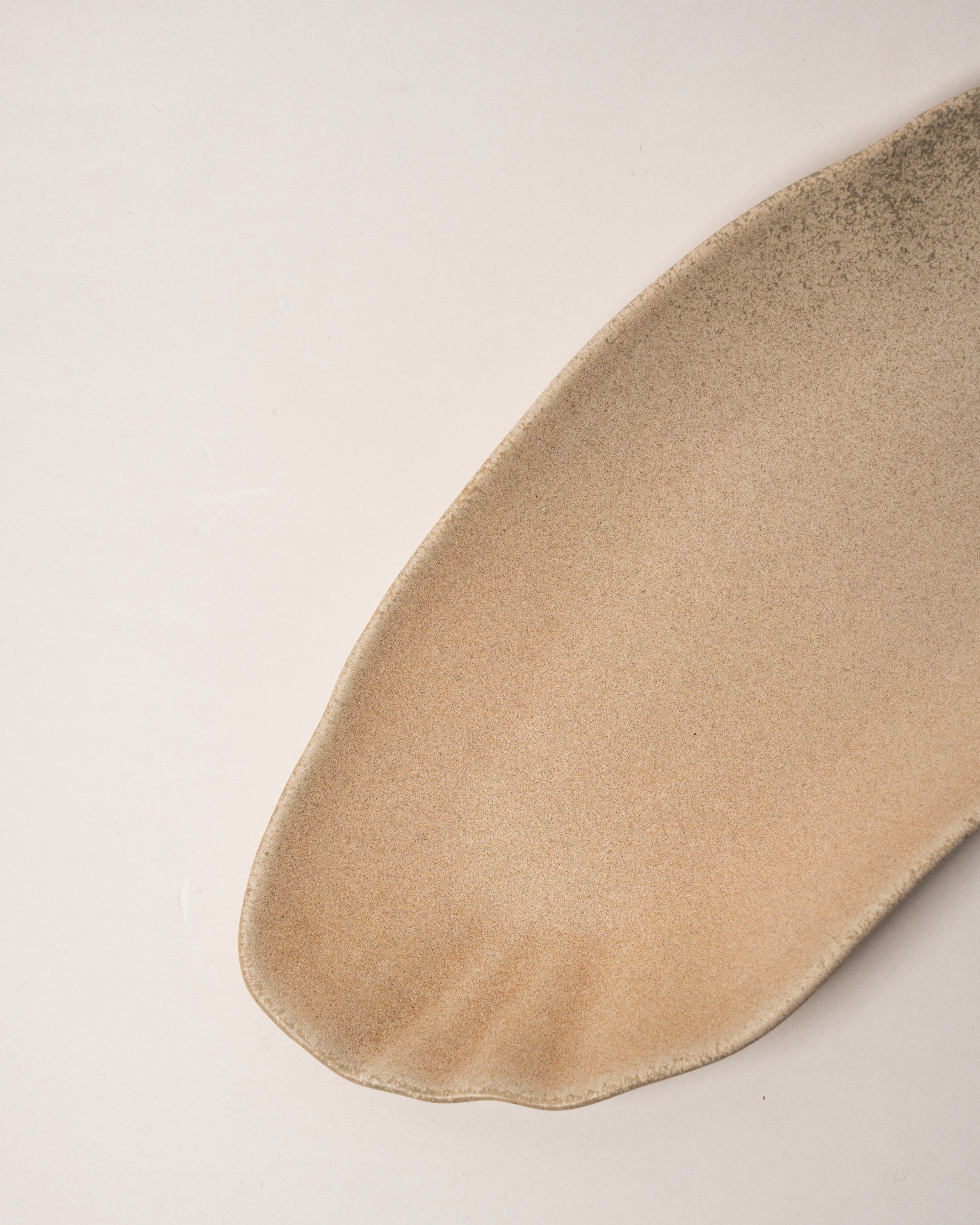 Angled view of Sahara porcelain rectangular plate showing sand-toned finish
