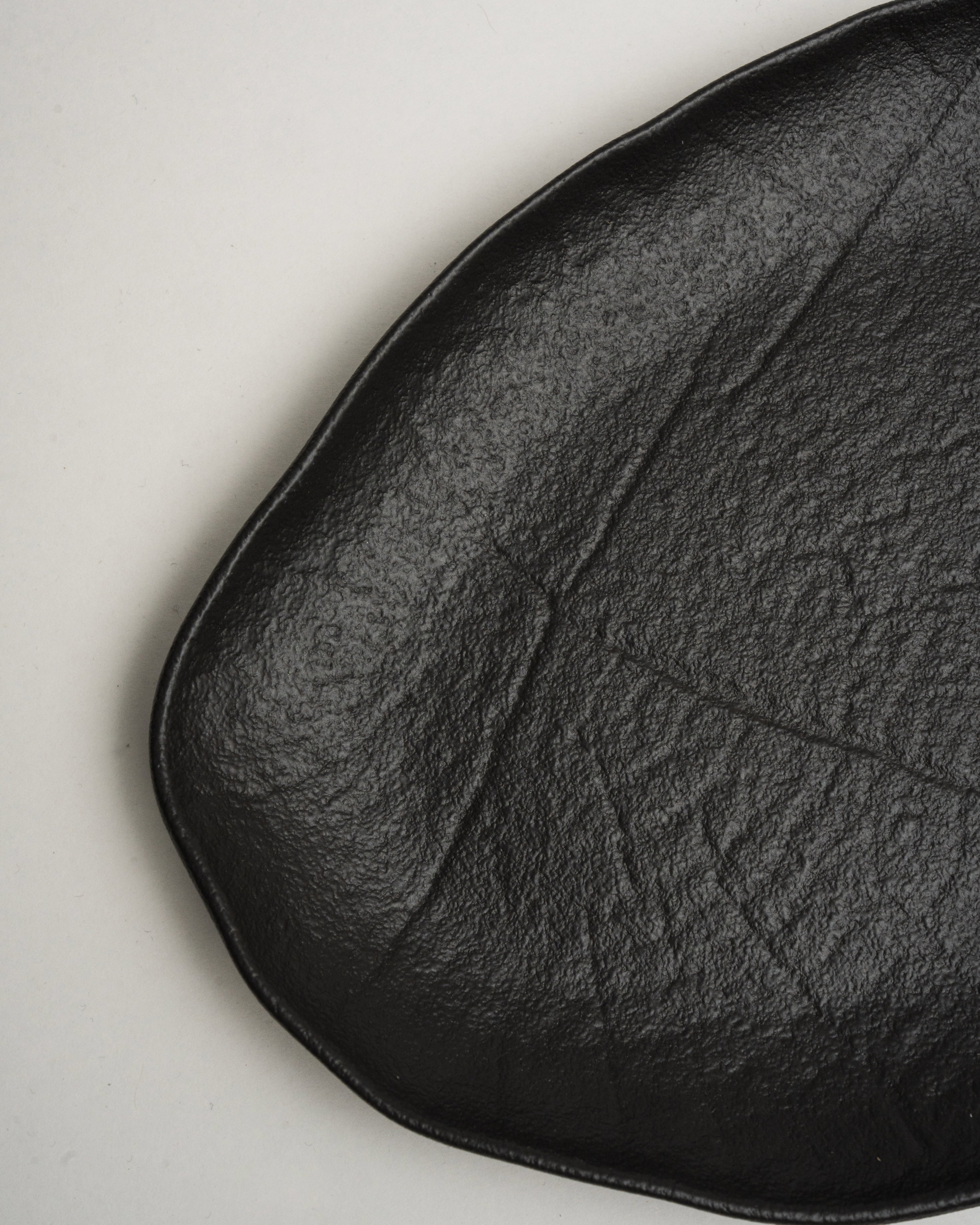 Angled view of Shade porcelain oval plate showing matte black finish