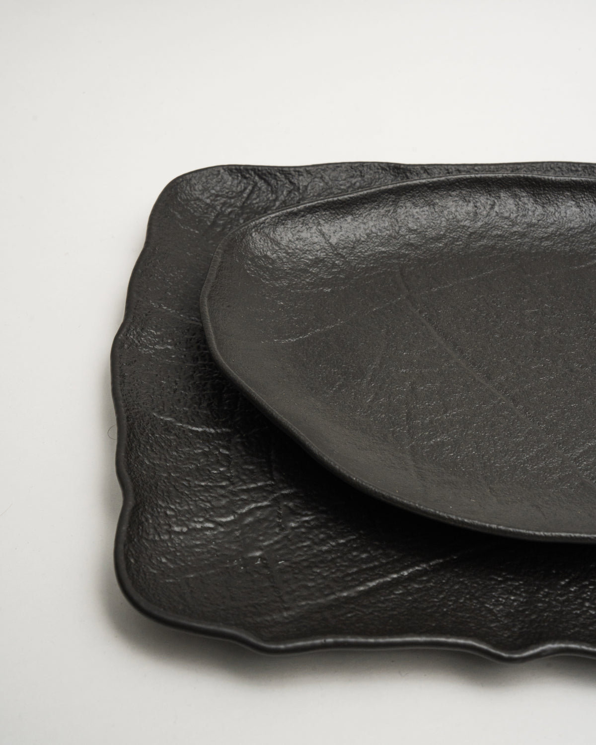 Side profile of Shade porcelain oval plate, matte black texture
