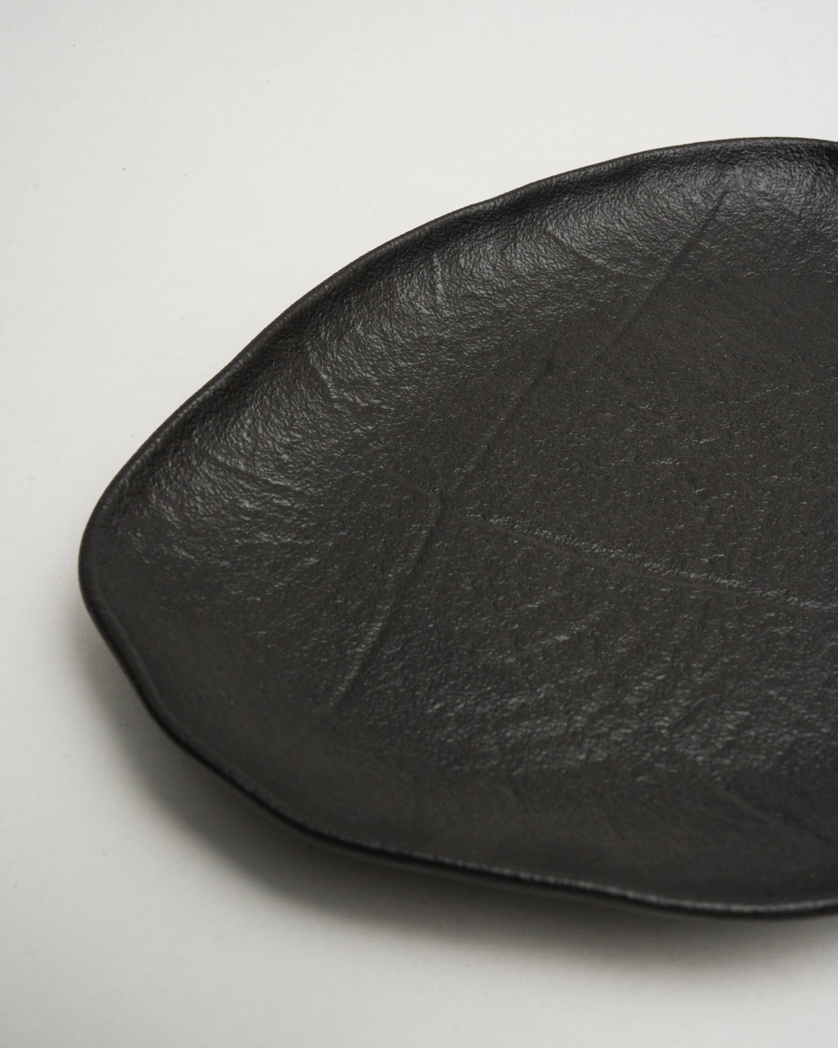 Tilted view of Shade porcelain oval plate, organic silhouette