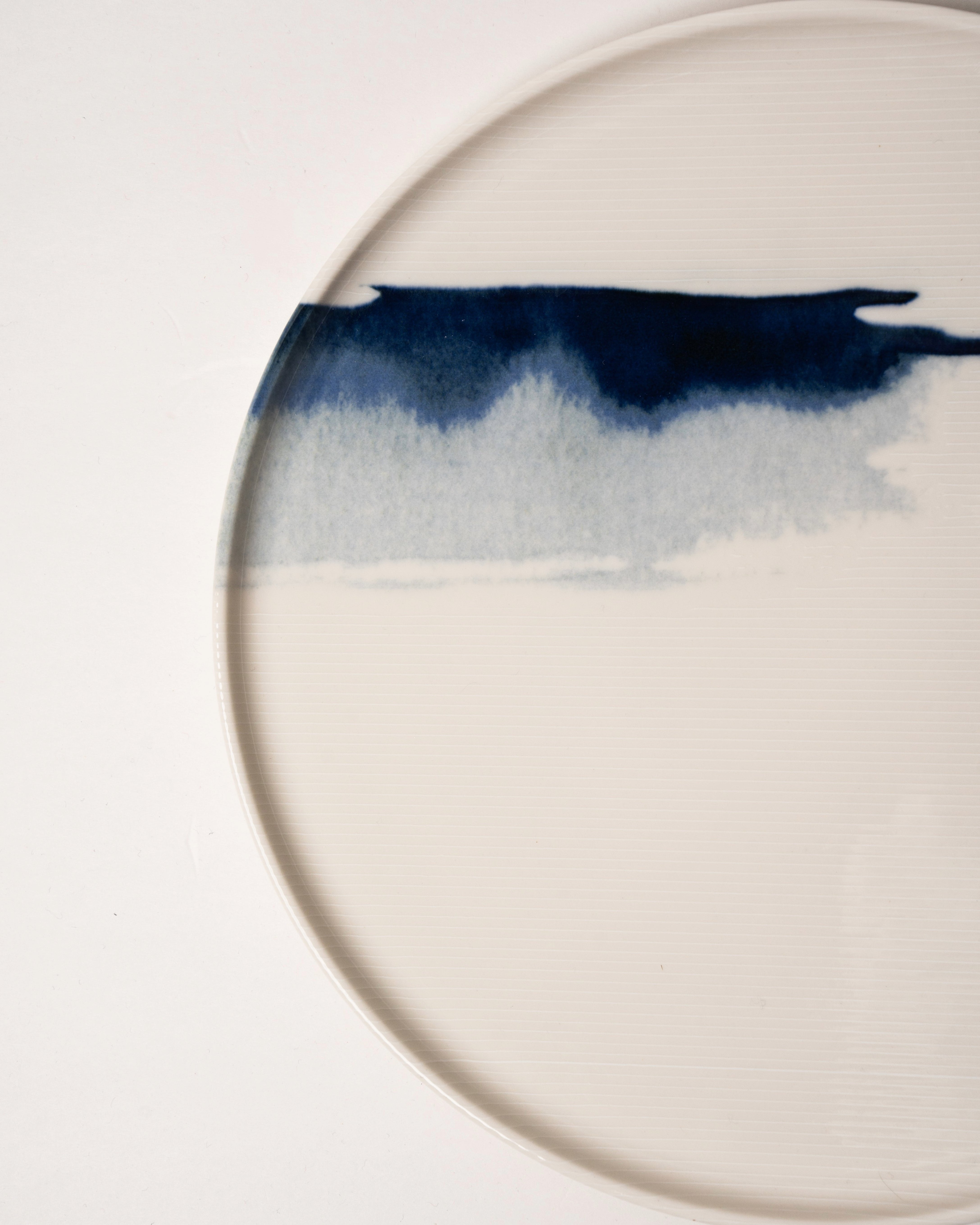Angled view of The Wave porcelain dinner plate showing wave detail