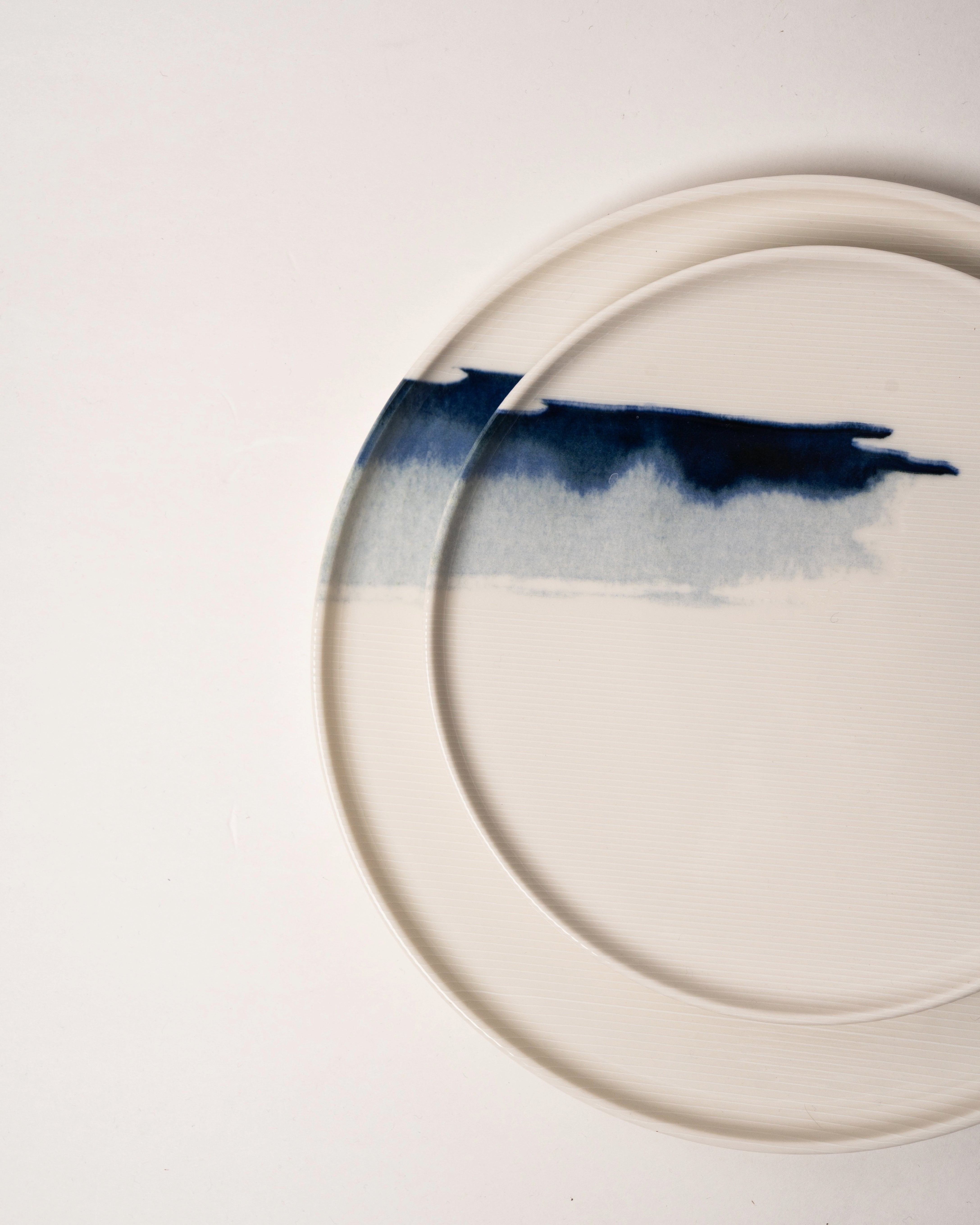 Angled view of The Wave porcelain dinner plate showing wave detail