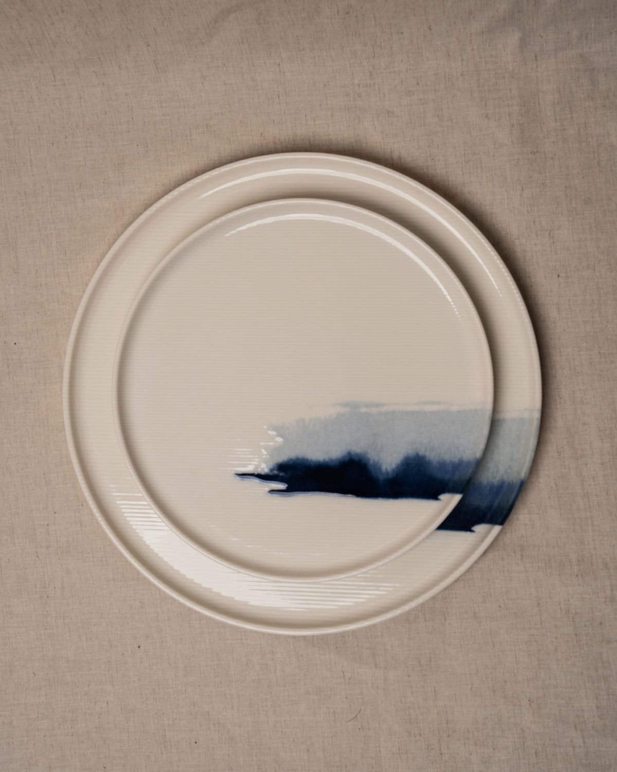 Close-up angled view of The Wave porcelain plate with blue wave brushstroke