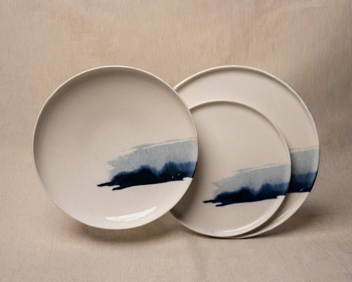 Three The Wave porcelain plates overlapping, blue wave pattern visible on both