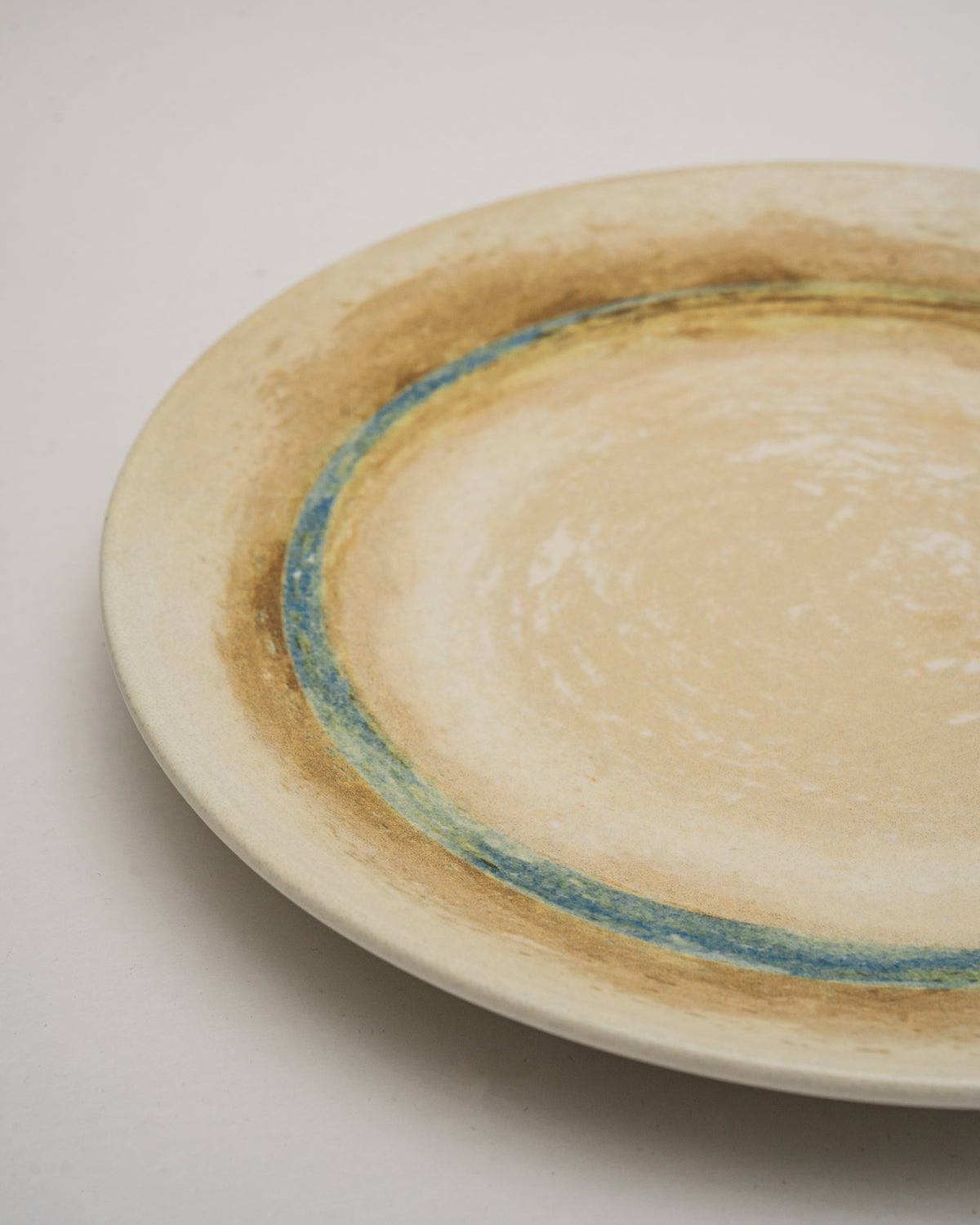Angled view of Tranquil porcelain dinner plate, sand-toned finish